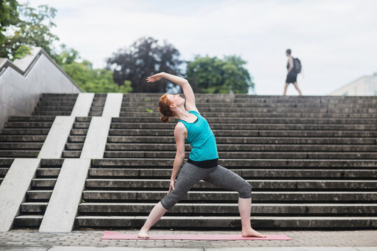 Young woman doing yoga on staircases in urban city, Freiburg im Breisgau, Baden-Württemberg, Germany
