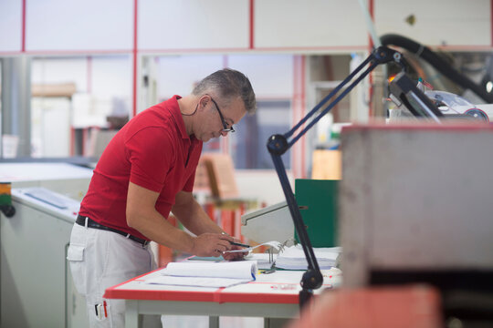 Male engineer examining circuit board in industry, Hanover, Lower Saxony, Germany