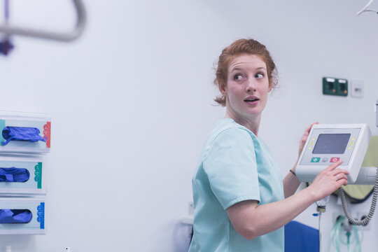 Female nurse looking over shoulder while operating medical equipment