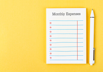 The Blank Monthly expenses planning checklist with pen on yellow background. For your text.