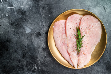 Uncooked Raw chicken chop breast fillets on a plate, poultry meat. Black background. Top view. Copy...