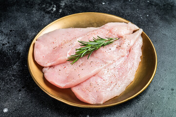 Uncooked Raw chicken chop breast fillets on a plate, poultry meat. Black background. Top view