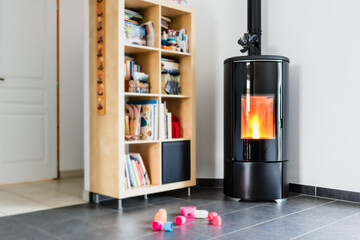 Pellet stove with some toys in front, with flames and library