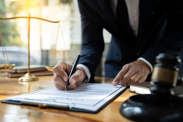Young Asian lawyer or legal advisor reading clarification on business agreement with the signing of the investment contract according to the laws and regulations in the office.