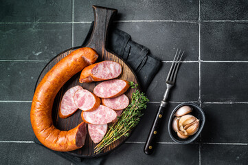 Sliced Krakow Smoked sausage on a wooden board. Black background. Top view