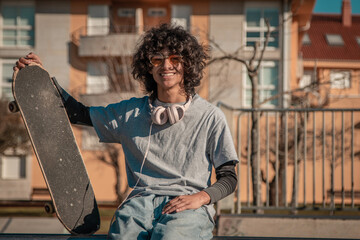 urban guy in headphones with skateboard sitting in skate park