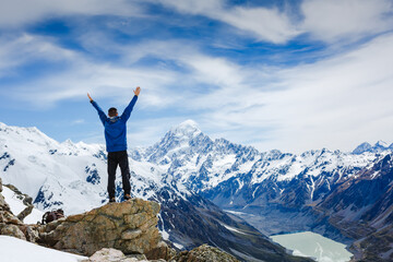 Winner / Success concept. Hiker cheering elated and blissful with arms raised in the sky after hiking to mountain top summit above the clouds