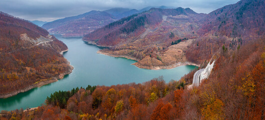 Amazing aerial view of a cliff coast road through mountains and autumn forests next to a lake Siriu...