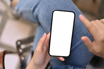 Top view of a female's hand holding a smartphone white screen mockup, using her smartphone
