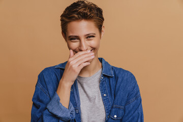 Young short-haired beautiful laughing woman covering her mouth with hand