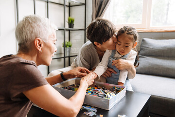 Obraz premium Grandmother kissing her little cute asian granddaughter holding puzzles