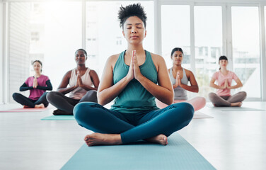 Obraz premium Yoga class, meditation and a black woman doing exercise for fitness, peace and wellness. Coach and diversity group in health studio for holistic workout, mental health and balance with prayer hands
