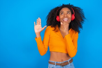 Happy young beautiful brunette woman wearing colourful dress over white wall sings favourite song...