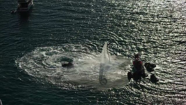 A man flies on a FlyBoard at sunset sea. Aerial. Water extreme sport, azure summer sea with outdoors active people enjoying water sports. Flyboarding and seariding, Recreation and sports concepts.