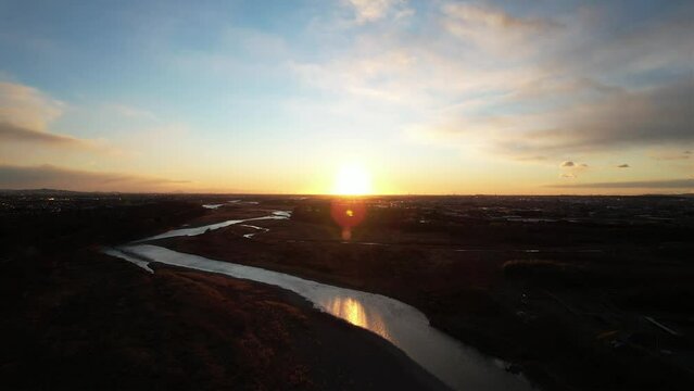 川の地平線に上に登る綺麗な朝日をドローン撮影