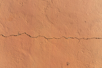 Wall painted orange with cracks in the plaster caused by the action of time. Beautiful texture.