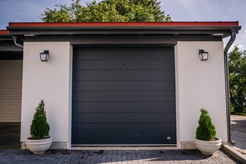 Modern gray garage, next to the Scandinavian-style house. Private garage with automatic door in a European 