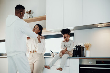 Little girl looks away as her parents get into an argument in the kitchen
