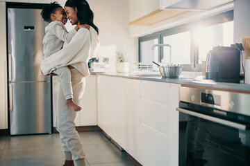 Single mother carrying her daughter in the kitchen