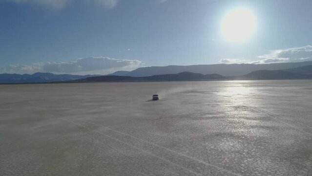 Dolly shot of off-road vehicle moving on Alvord Desert against sky during sunny day