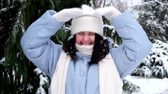 happy woman in winter clothes rid snow on her hat