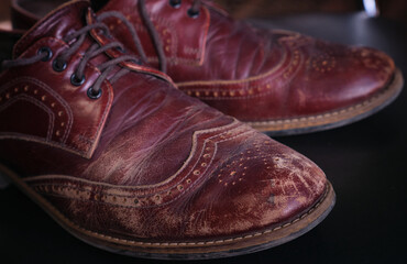 Fototapeta na wymiar Close up worn old red brown leather scratches and scuffs on men oxford shoes