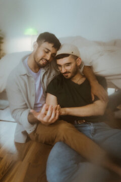 Gay couple spending leisure time sitting at home