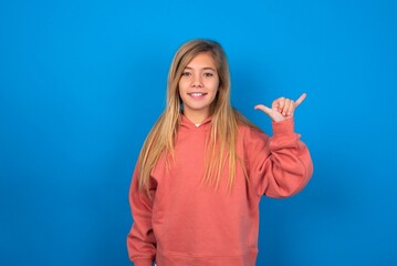 beautiful caucasian teen girl wearing pink sweater over blue wall showing up number six Liu with...