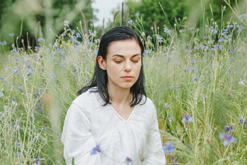 Beautiful girl among the summer field with wildflowers