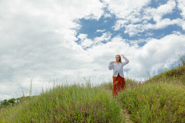 beautiful girl in white shirt and orange skirt against blue sky and clouds