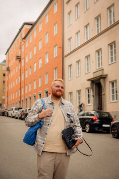 Smiling obese man with bag walking in front of building at street