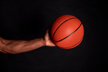 african man hands holding a basketball, black background