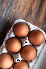 Brown eggs in a cardboard tray on a wooden background