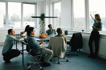 Businesswoman conducting meeting with colleagues sitting at desk in office