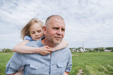 Obraz premium Daughter embracing father carrying her piggyback.