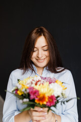 pregnant happy woman in a blue shirt holding a bouquet of flowers