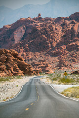Straight road in the Valley of Fire and reddish rocks in the backgrnd