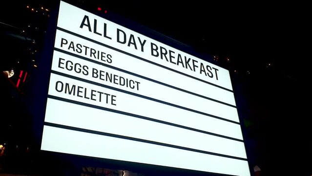 All day breakfast, pastries, eggs benedict and omelette neon LED sign surrounded by flashing fairy lights at diner restaurant cafe