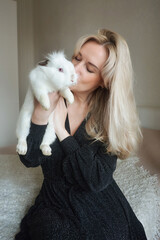 beautiful young blonde woman holding a white rabbit. pets. background for decoration for the holidays. Happy Easter