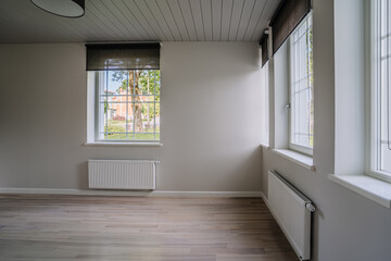 Classical empty room interior. The rooms have wooden floors and gray walls ,decorate with white moulding,there are white window looking out to the nature view.