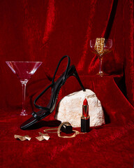 Still life studio shot of a luxury set with black high heel sandal shoe, crystal glasses, golden...