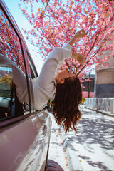 woman get out of the car blooming sakura tree on background
