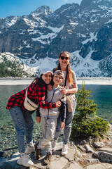 A family are standing on the shore of a lake. Morskie Oko, Tatras mountains.