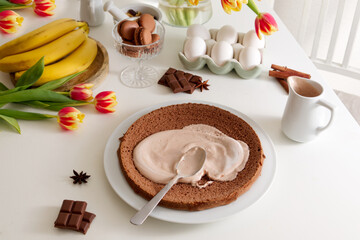 Biscuit chocolate cakes smeared with cream on the table next to the products needed for the cake