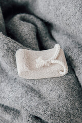 Pumice stone laid on a cozy grey wool sweater, shot in studio with soft window light