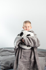 A six-year-old boy plays with a stuffed toy in the form of a soccer ball on the bed.A six-year-old boy plays with a stuffed toy in the form of a soccer ball on the bed.hugs the ball