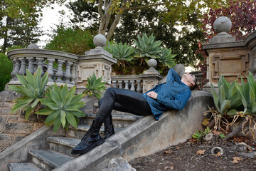 portrait of handsome brunette man wearing fantasy medieval prince costume with romantic silk shirt. sitting pose on balcony in historical castle location background.