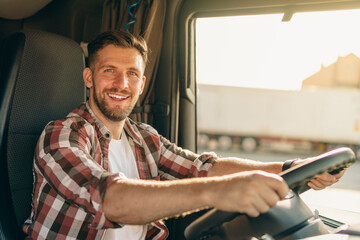 Professional middle aged truck driver in casual clothes driving truck vehicle going for a long...