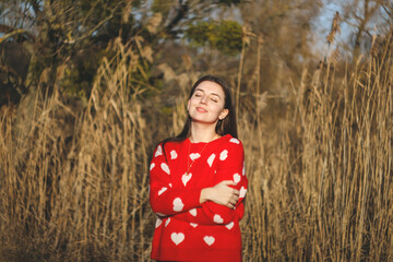 Woman in red sweater with hearts posing.Rays of the sun.Valentine's Day.Emotions of happiness and...