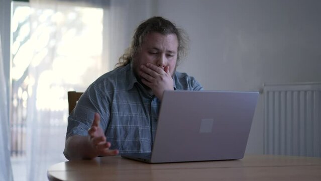 One sad man feeling despair in front of laptop computer. Unhappy emotion of a male fat person not liking result online feeling frustration